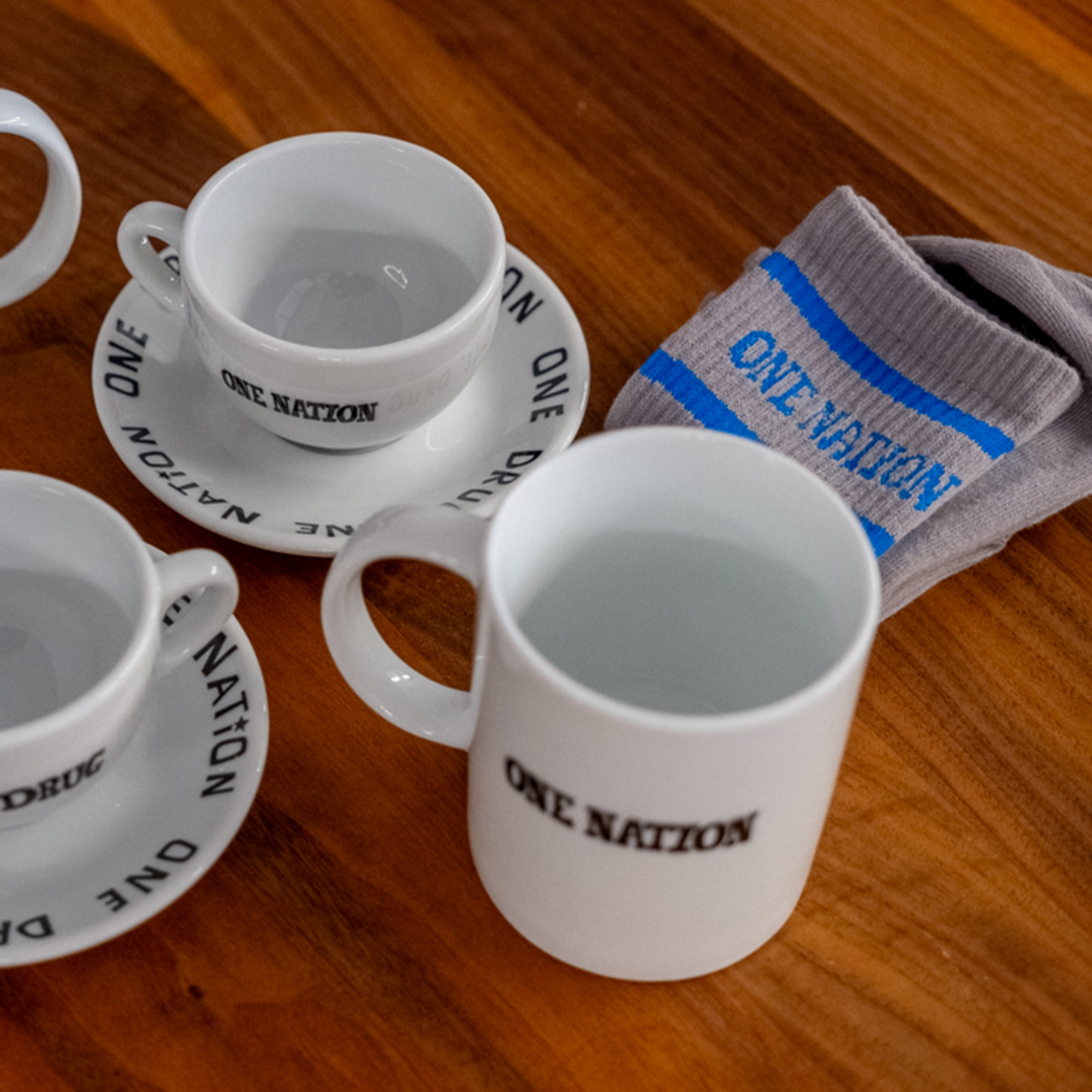 Caffenation One Drug cups, saucers and socks arranged on a wooden table