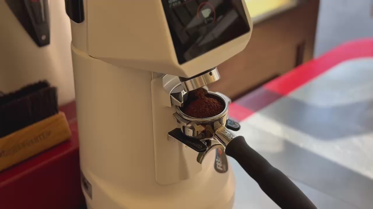 A grinder dosing freshly ground coffee into an espresso portafilter